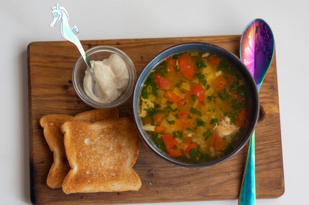 A vibrant and inviting image of a homemade chicken soup with rice garnished with fresh herbs in a cozy bowl emanating wa
