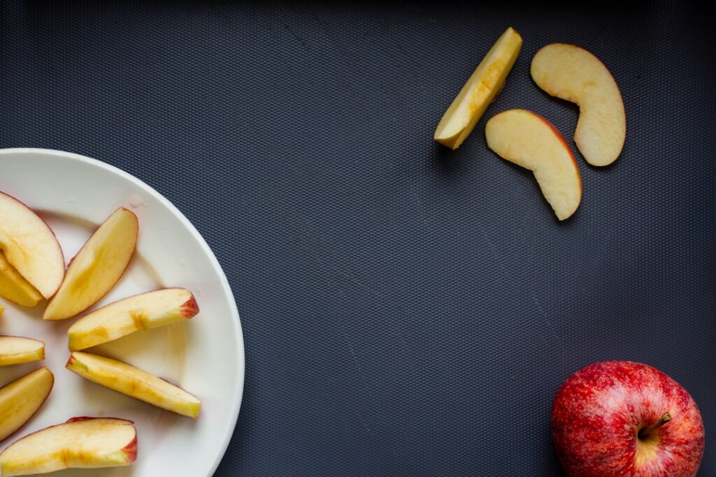 Crisp red apple slices generously spread with creamy almond butter on a small plate demonstrating a balanced snack combi