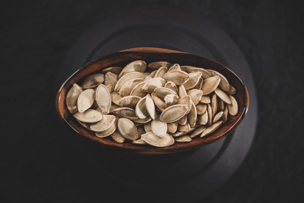 A serene natural light image of a small inviting evening snack sliced kiwi and a small bowl of pumpkin seeds on a wooden