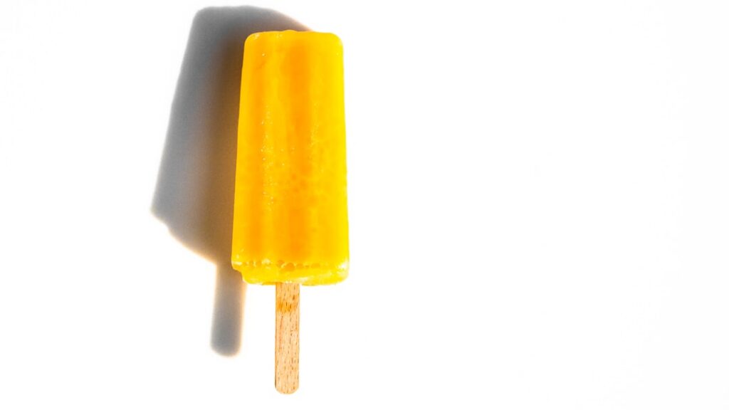 Vibrant sun-drenched image of tropical mango tango pudding pops bright orange maybe with a slice of fresh mango or a spr