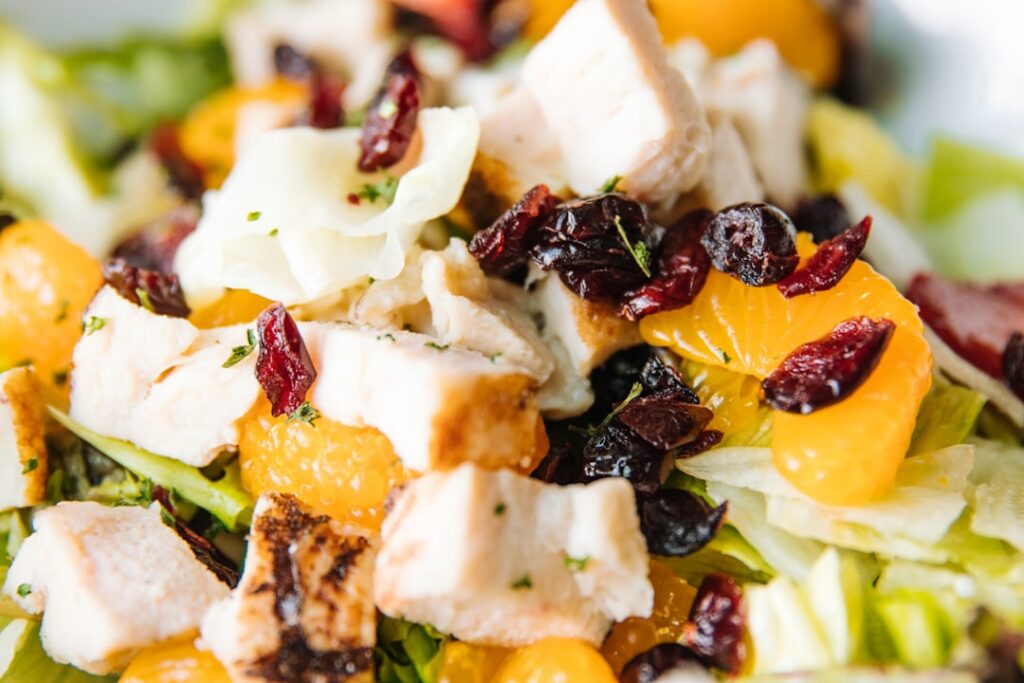 A close-up shot of a healthy and vibrant Cranberry Almond Chicken Salad in a transparent meal prep container The focus i