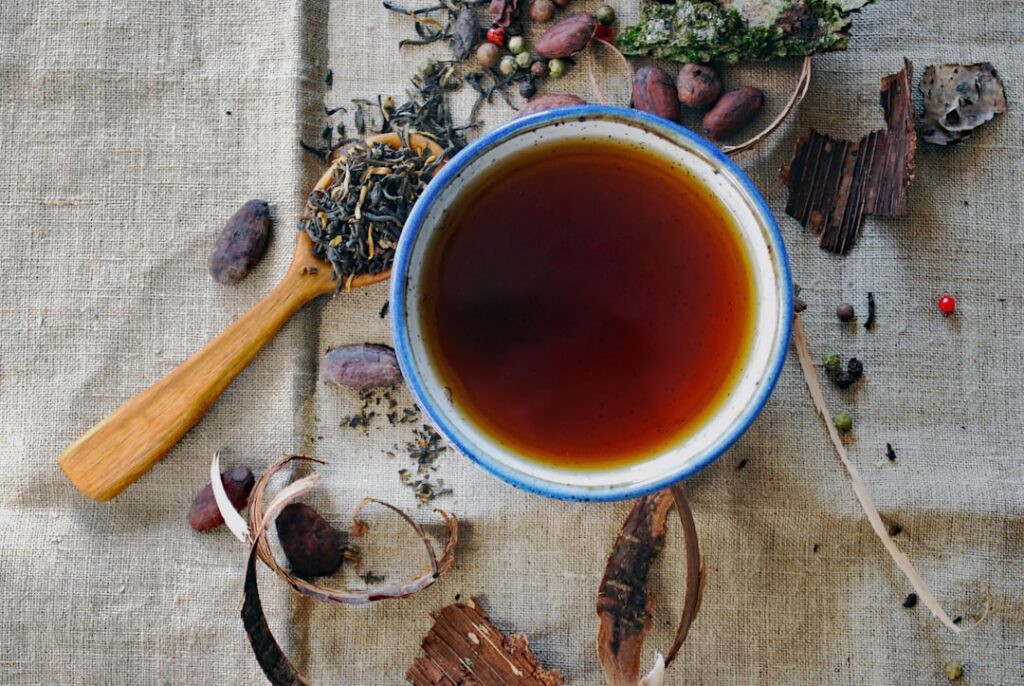 A traditional herbalist preparing an infusion of dried herbs in a rustic setting with steam gently rising from a mug or 