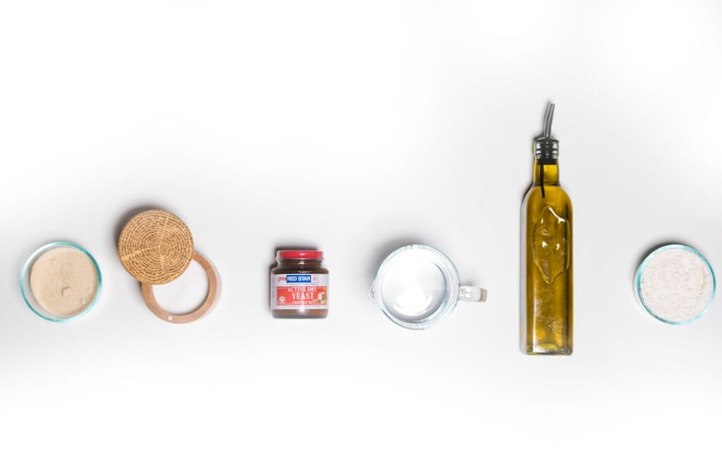 Various natural ingredients including a whole and half tomato honey in a dipper coconut oil in a bowl and a jar of Vasel
