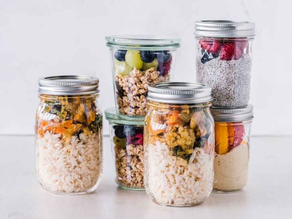 A variety of fresh colorful meal prep ingredients laid out on a clean kitchen counter ready for assembly into lunch jars