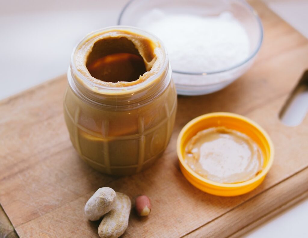 A close-up shot of a creamy indulgent peanut butter cup protein smoothie in a glass topped with a drizzle of peanut butt