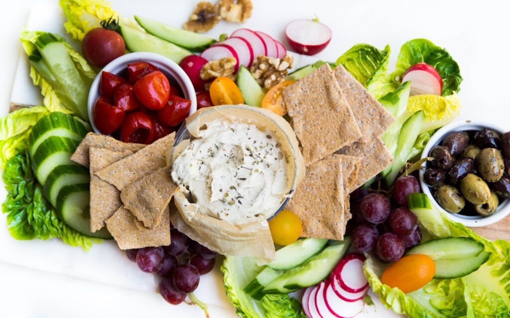 A close-up shot of a variety of colorful appetizing dips like hummus guacamole and a creamy white dip served in small bo