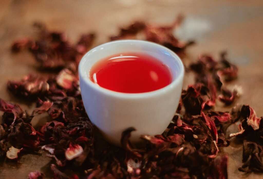 Close-up of vibrant dried hibiscus petals in a small ceramic bowl highlighting their rich red color