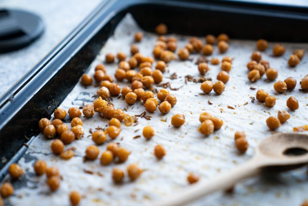 A beautifully arranged sheet pan with roasted chickpeas colorful bell peppers zucchini and red onion seasoned with herbs