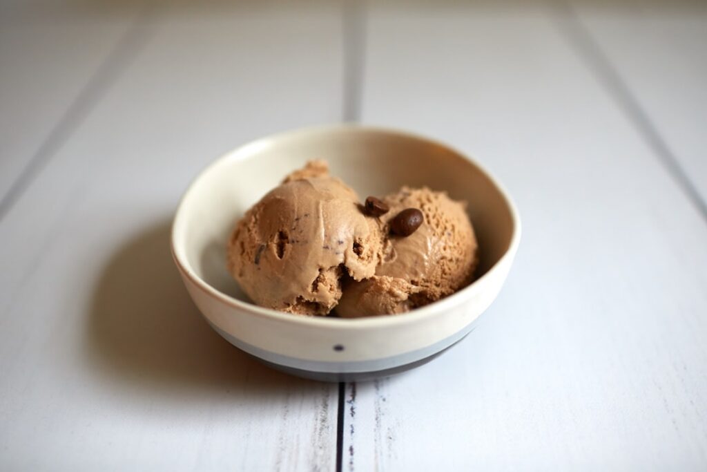 A close-up appealing shot of a bowl of creamy high-protein peanut butter swirl ice cream drizzled with natural peanut bu