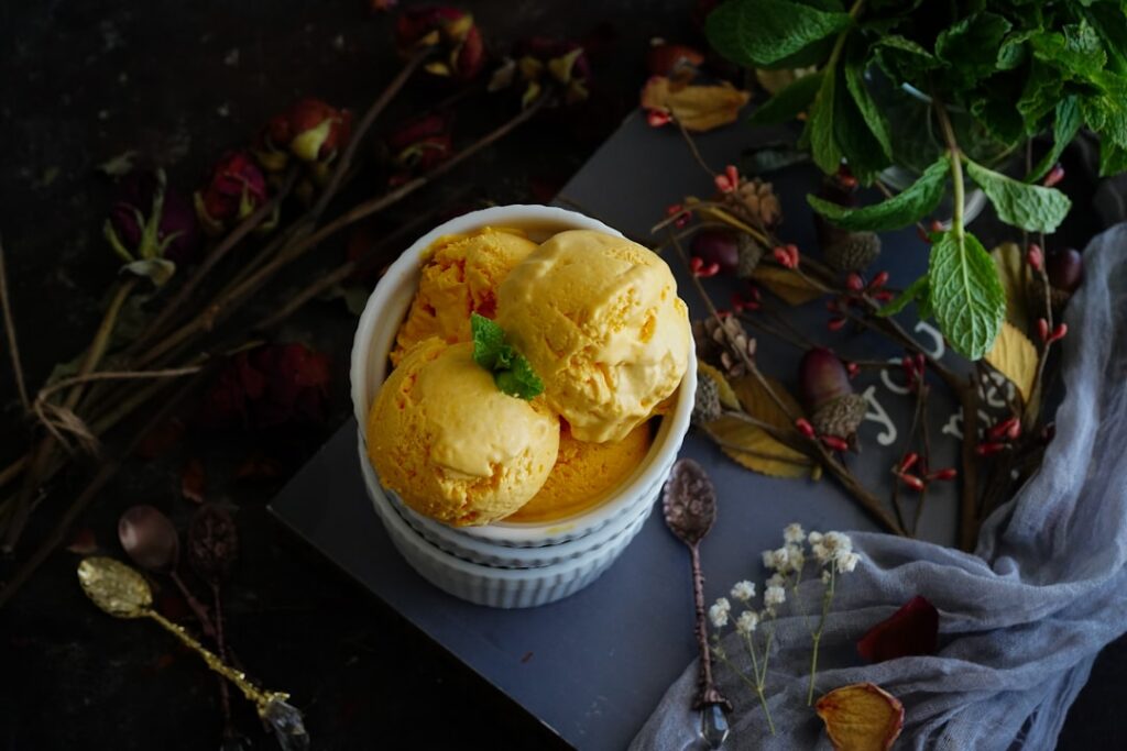 A vibrant and fresh bowl of high-protein tropical mango cheesecake ice cream garnished with fresh mango cubes and toaste