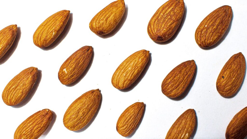 Hands applying a golden oil to the face with whole cloves crushed cloves almond oil and a small dropper bottle in the ba