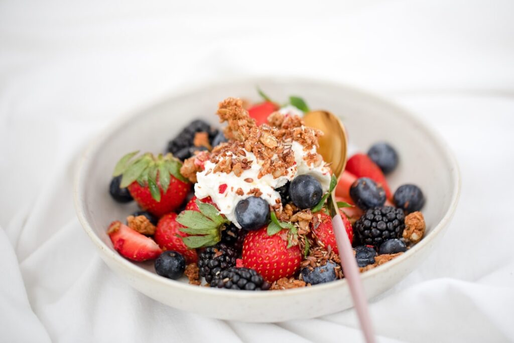 A beautifully presented whipped cottage cheese bowl topped with a colorful array of fresh mixed berries a sprinkle of gr