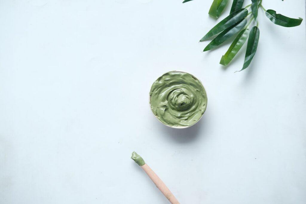A mashed ripe avocado mixed with olive oil in a bowl with a small whisk ready to be applied as a hydrating hair mask