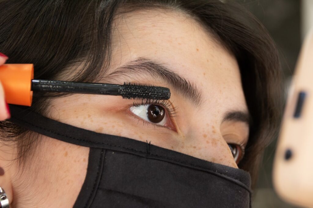 A close-up shot of a hand holding a clean mascara wand applying a clear serum to a person s eyelashes gently with a soft