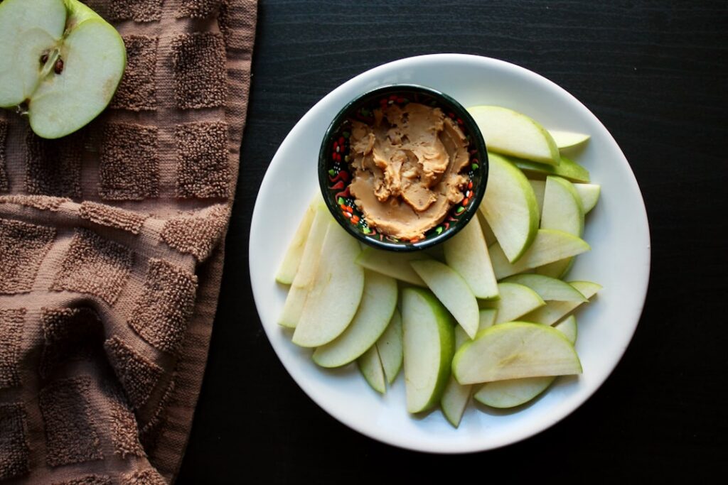 Crisp apple slices artfully arranged around a small dollop of creamy almond butter on a minimalist plate