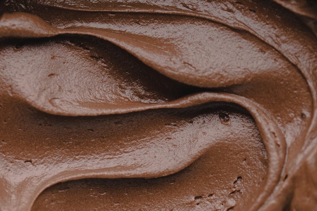 Close-up shot of creamy chocolate avocado mousse in a small glass bowl garnished with a sprinkle of cocoa powder The tex