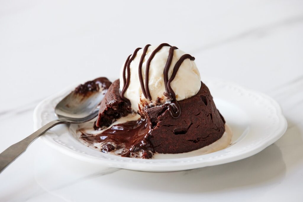 A close-up top-down view of a rich fudgy chocolate mug cake in a white ceramic mug possibly with a light dusting of coco