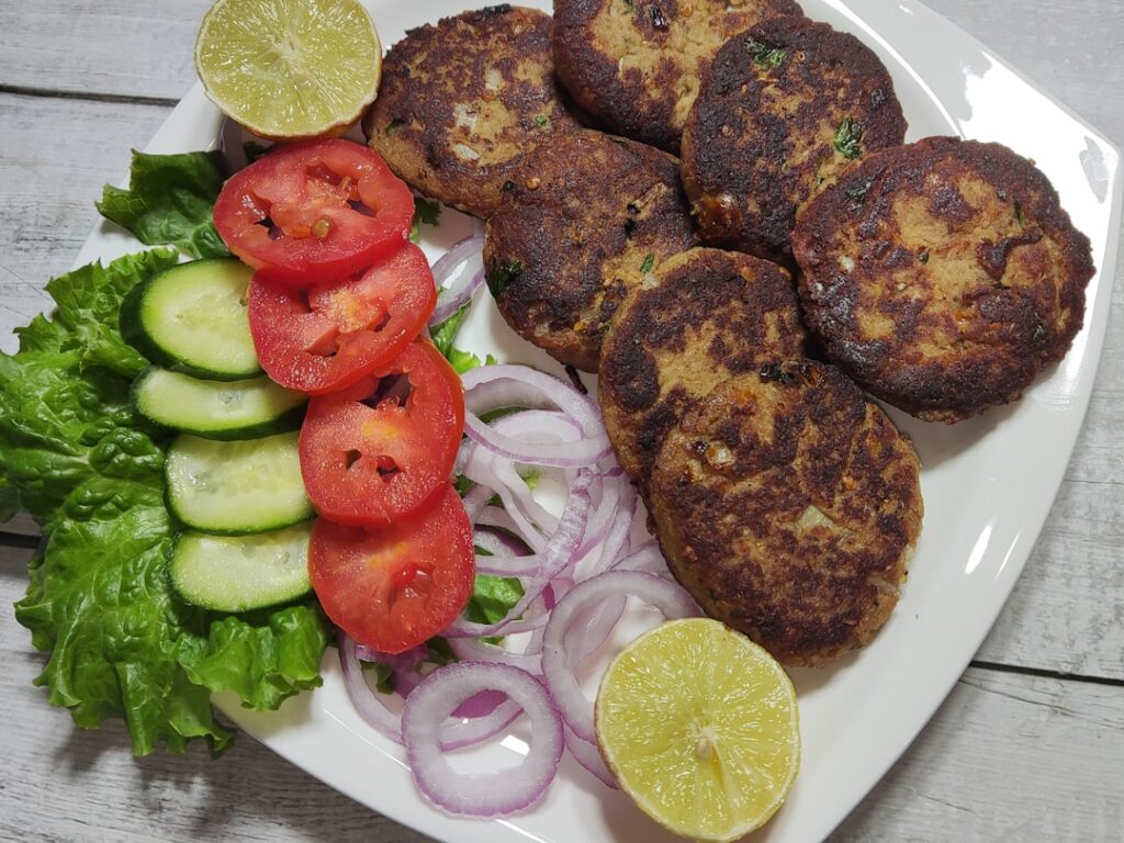 A close-up shot of homemade chickpea fritters golden brown and crispy stacked on a plate with fresh herbs and a dipping 