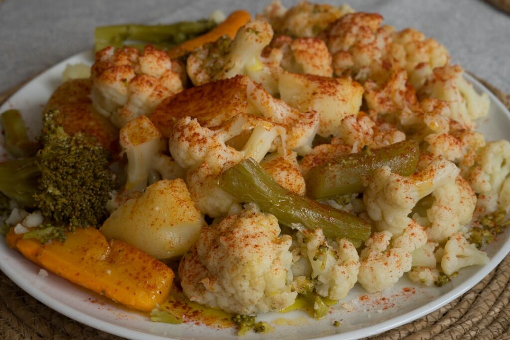A close-up of perfectly roasted cauliflower florets golden brown and slightly crispy in an elegant bowl on a rustic wood