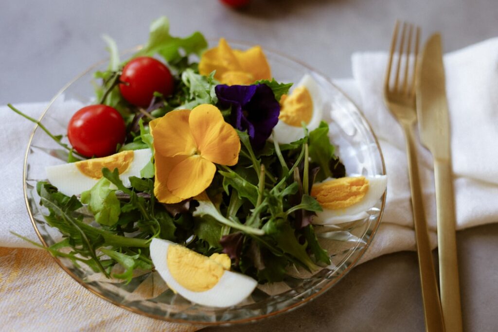 A close-up of a vibrant salad garnished with colorful edible flowers like pansies nasturtiums and borage blossoms