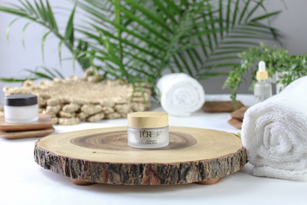 A small elegant glass jar containing a light brown translucent gel clove aloe vera elixir with a tiny wooden spoon on a 