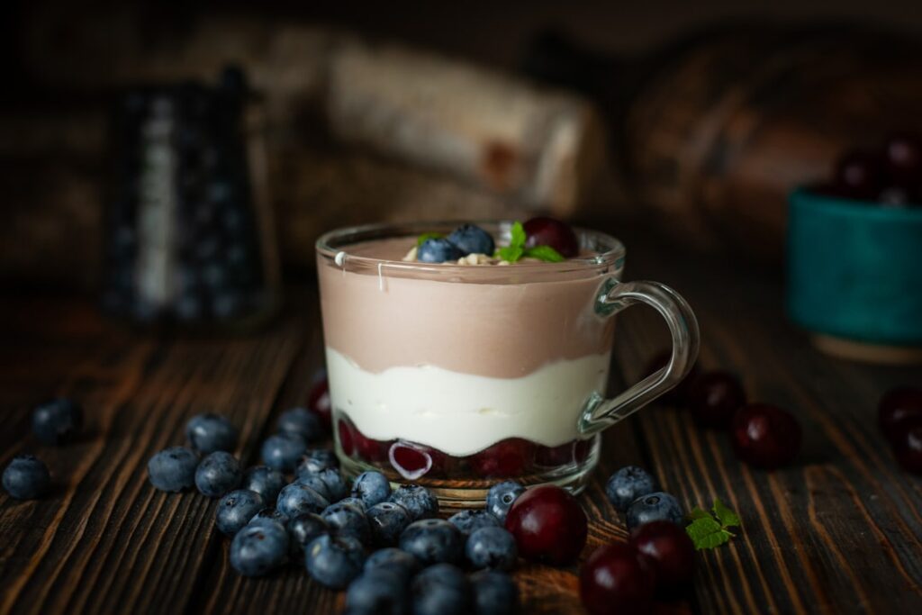A vibrant top-down view of a blueberry cheesecake mug cake in a white ceramic mug garnished with fresh blueberries