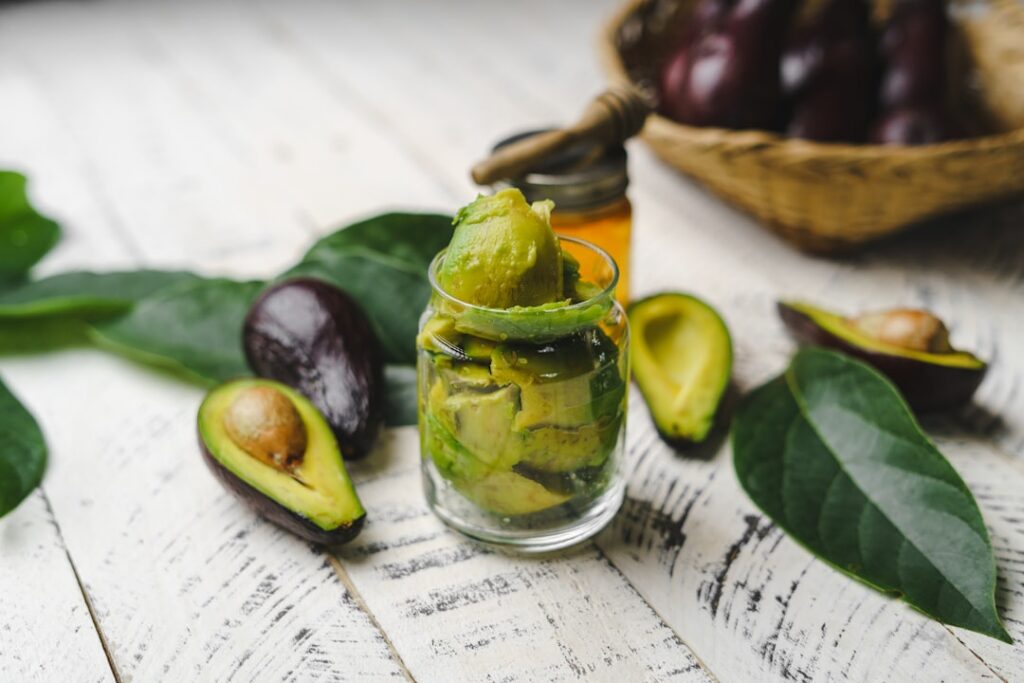 Small corked glass bottle of golden avocado oil with a label on a wooden board
