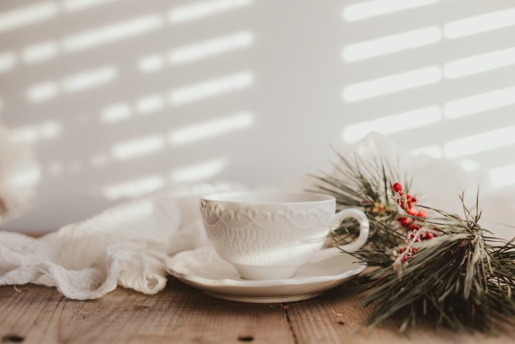 A clear glass cup filled with a light green purslane tea with some fresh purslane sprigs next to it on a rustic wooden t