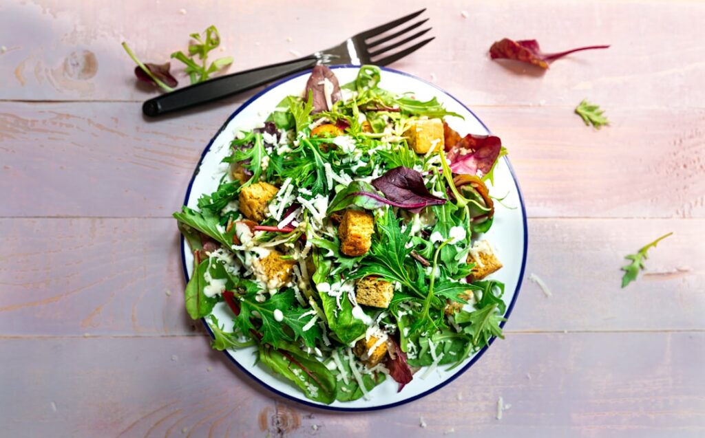A bowl of fresh purslane salad with chopped tomatoes and cucumber drizzled with olive oil and lemon juice