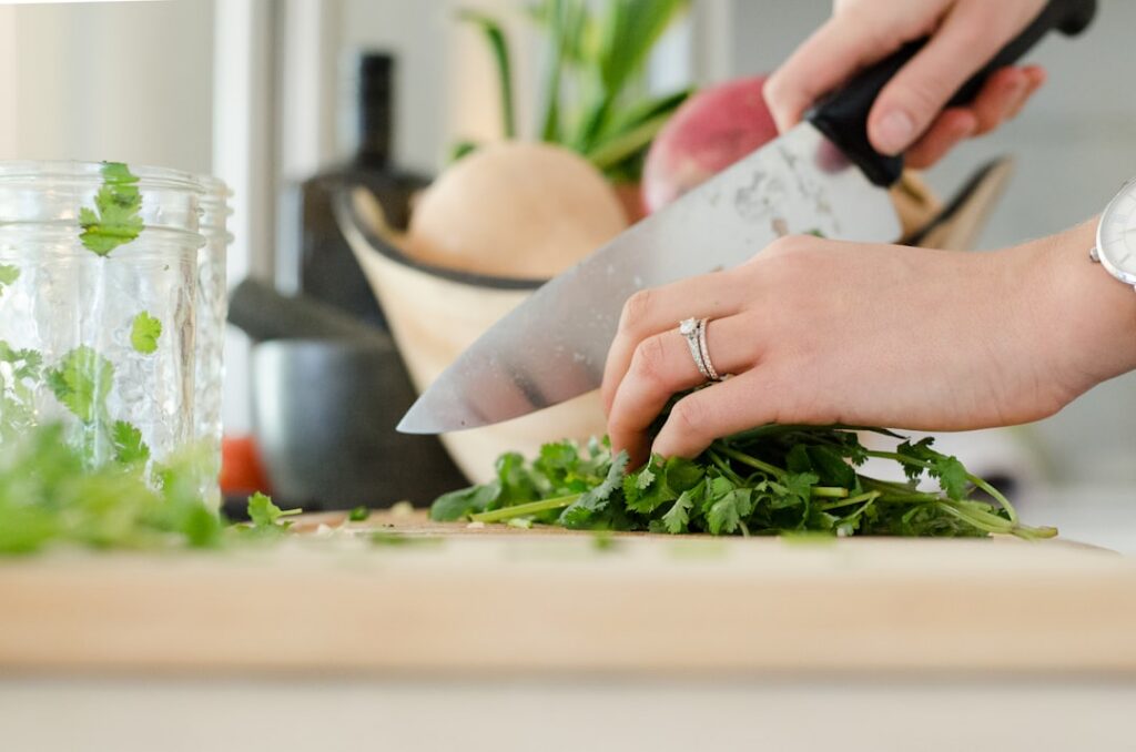 Close-up of fresh clean dandelion leaves being chopped on a wooden cutting board
