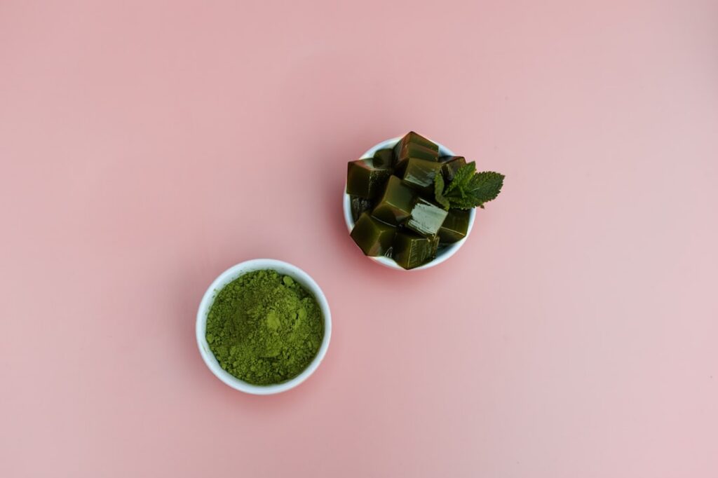 Dried papaya leaves and a small bowl of fine papaya leaf powder with a mortar and pestle in the background