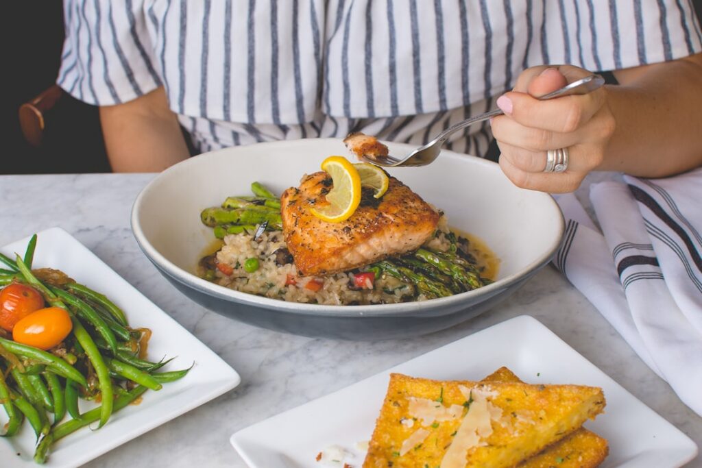 A perfectly cooked salmon fillet served with roasted asparagus and lemon wedges on a white plate showcasing a healthy an