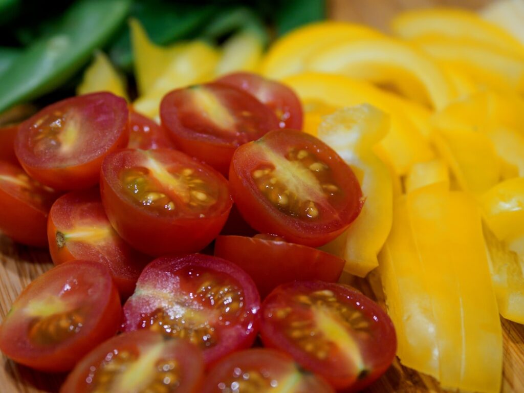 A close-up of sliced fresh ginger root and ripe tomatoes ready to be prepared for a healthy drink or meal