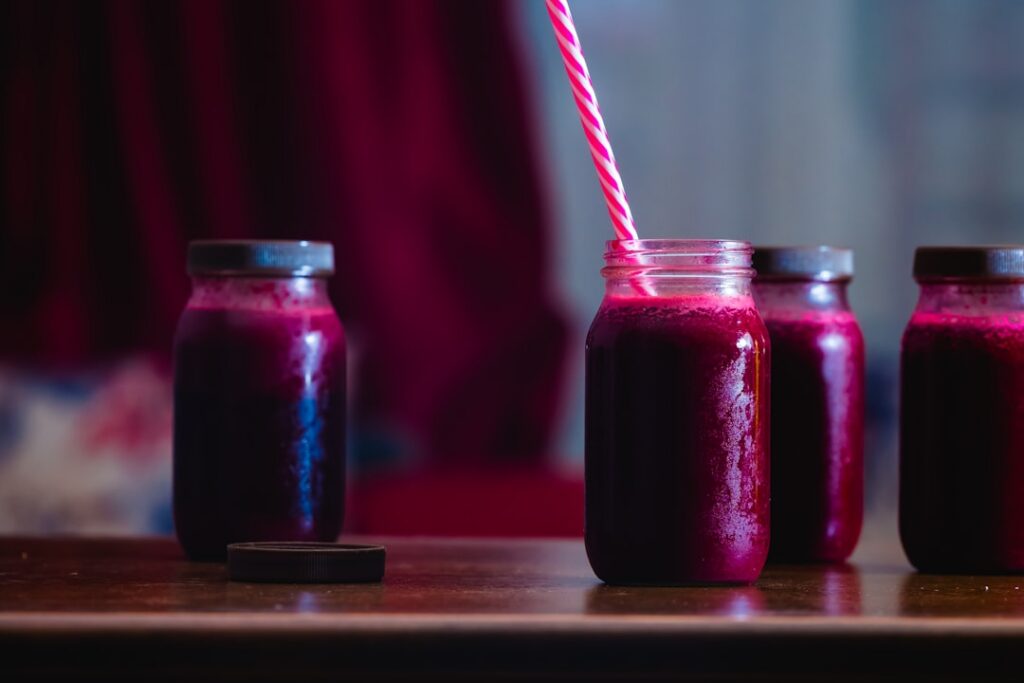 A clear glass bottle filled with vibrant red beet ginger lime and garlic juice sealed with a lid and stored in a refrige