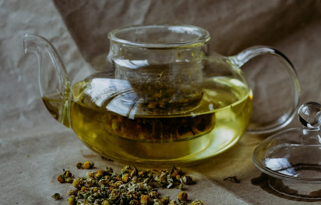 A steaming cup of chamomile tea with a slice of lemon on the rim set on a cozy wooden table with soft light evoking warm