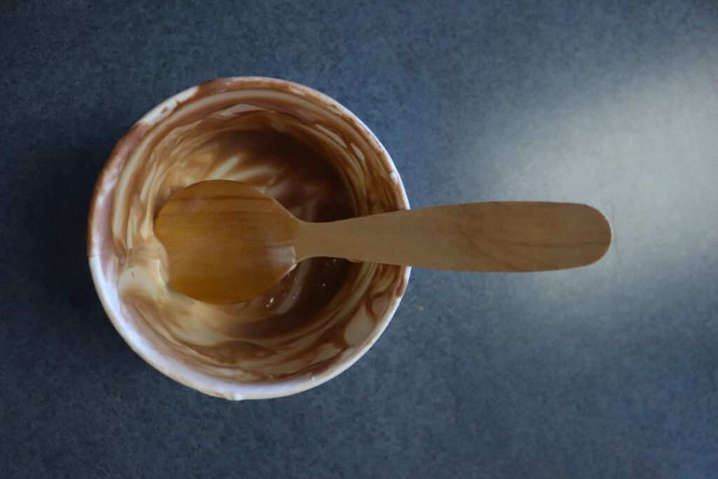 Close-up shot of a glass bowl filled with fresh coffee grounds plain yogurt and golden honey mixed together to form a cr