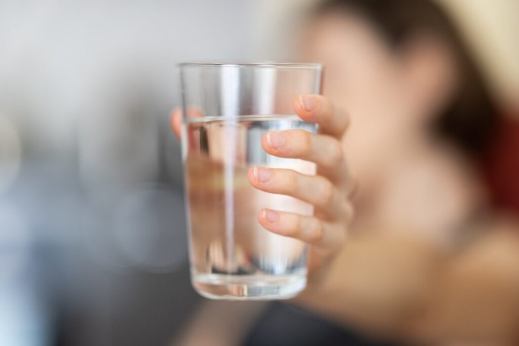A person drinking a glass of water emphasizing hydration with a focus on overall wellness