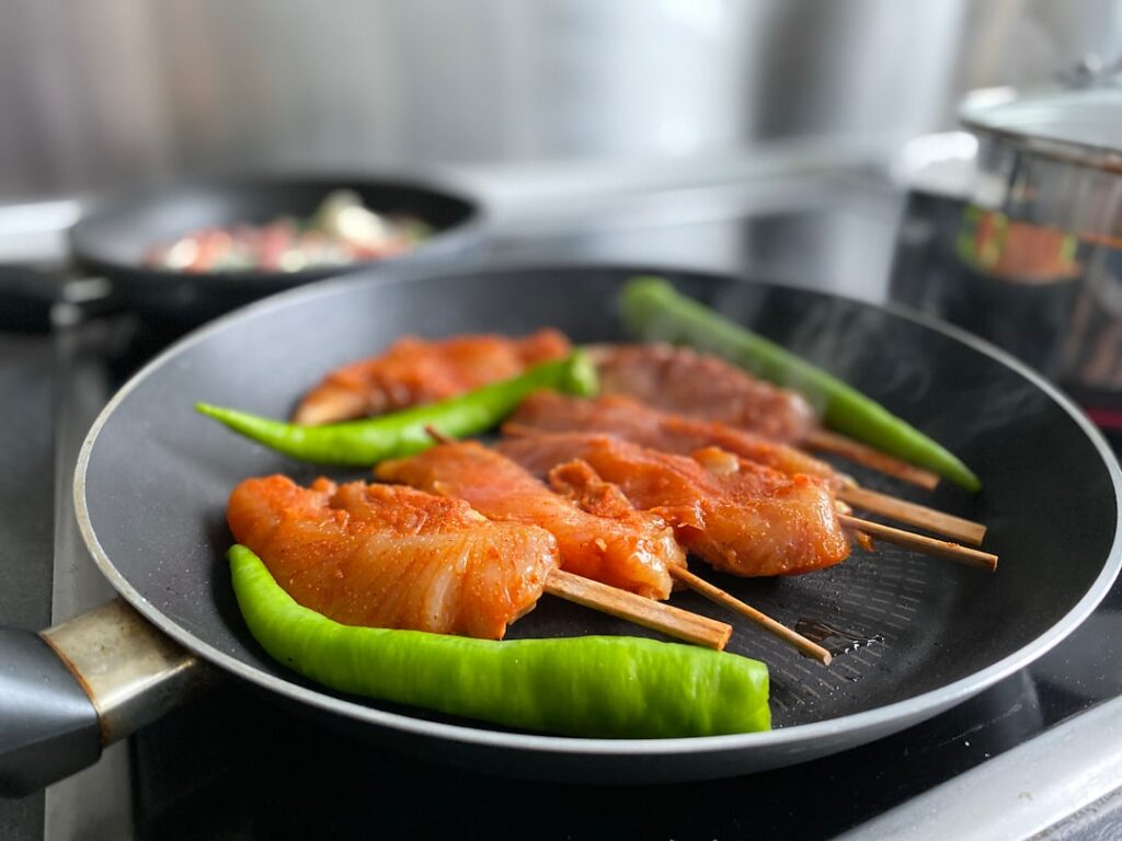 Various fresh ingredients for chicken seekh kebab laid out neatly in small bowls minced chicken chopped onion ginger-gar