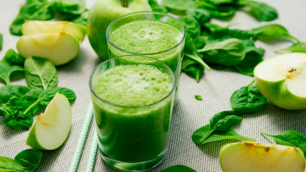 A close-up shot of a refreshing green apple cucumber and mint shake in a glass with fresh ingredients artfully arranged