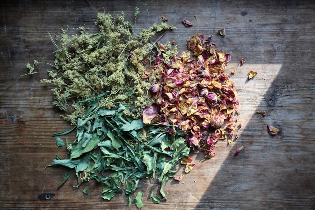 Close-up of dried Mullein leaves and yellow flowers in a bowl with a mortar and pestle nearby on a rustic wooden surface