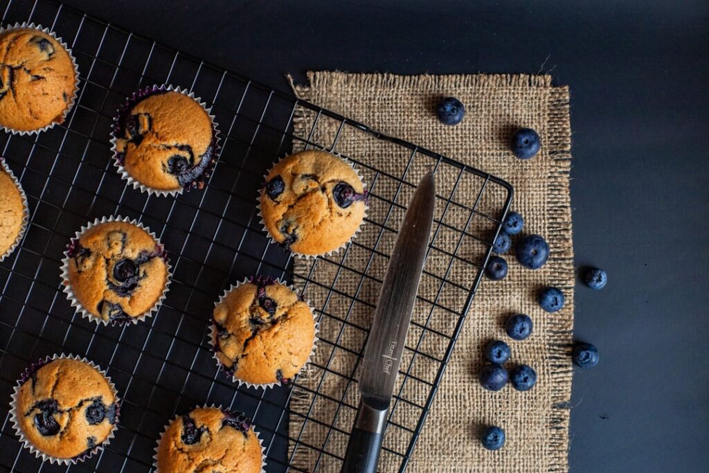 A close-up shot of freshly baked fluffy vegan blueberry muffins some with blueberries visible on top arranged beautifull