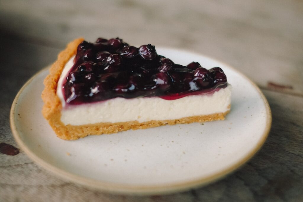 A beautiful slice of no-bake vegan cheesecake topped generously with a mix of fresh colorful berries like strawberries b