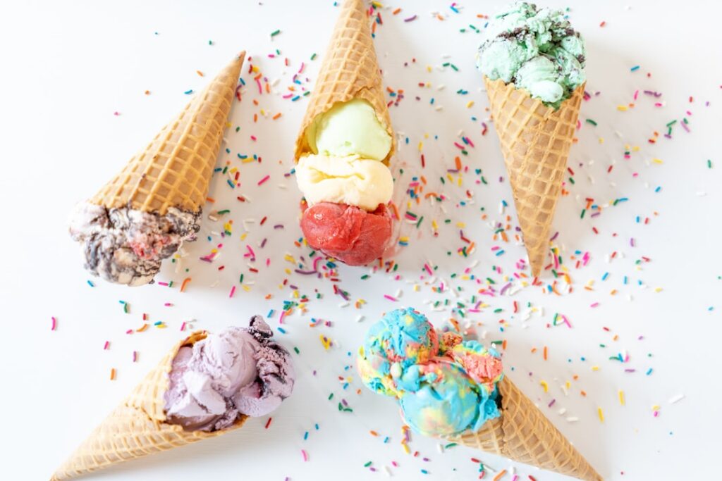 An assortment of six different healthy homemade ice cream flavors in aesthetic bowls or cups garnished with fresh fruit 