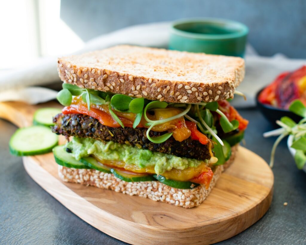 A perfectly constructed colorful and healthy sandwich with visible layers of fresh ingredients like whole-grain bread le
