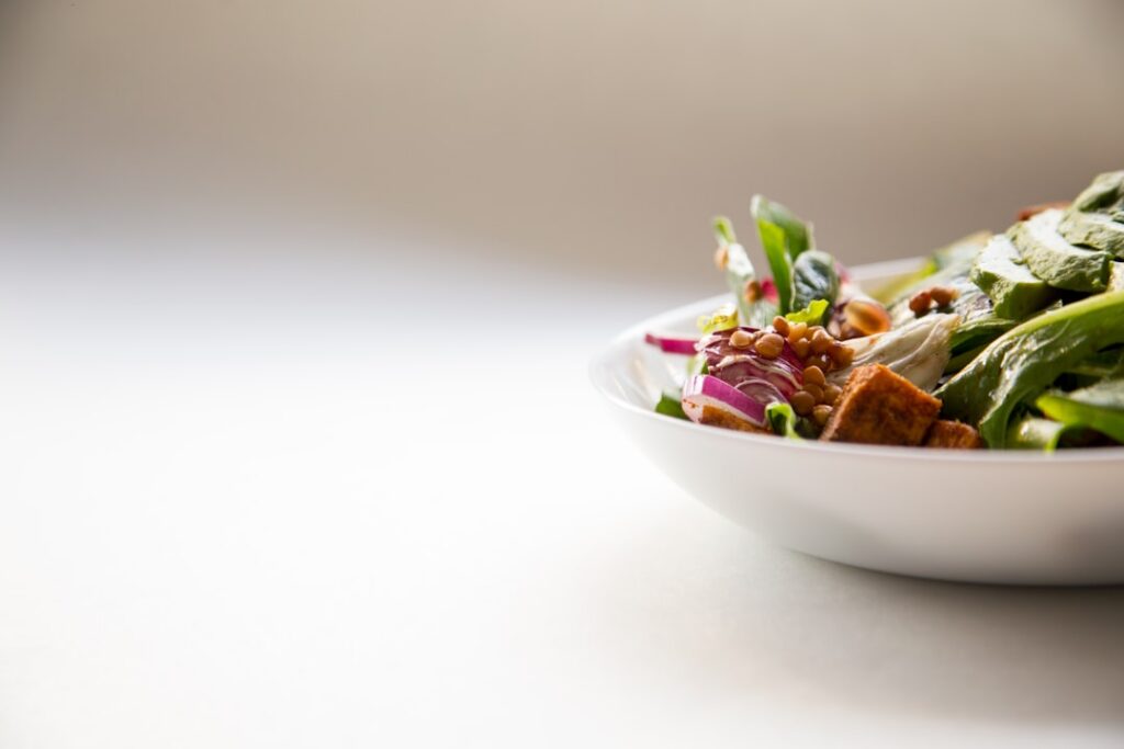 A vibrant diverse salad bowl filled with various leafy greens like spinach kale romaine and arugula along with some colo