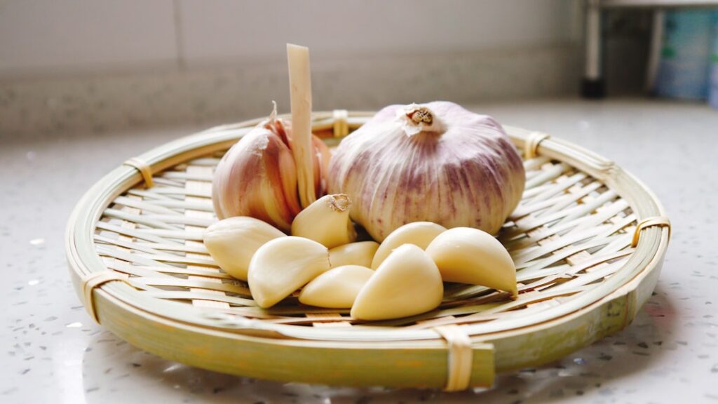A close-up of garlic cloves red onions and whole cloves arranged together on a rustic wooden surface symbolizing natural