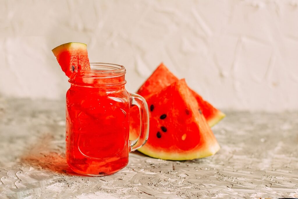 A vibrant flat lay of kidney-friendly foods and drinks including slices of watermelon a glass of coconut water a mug of 