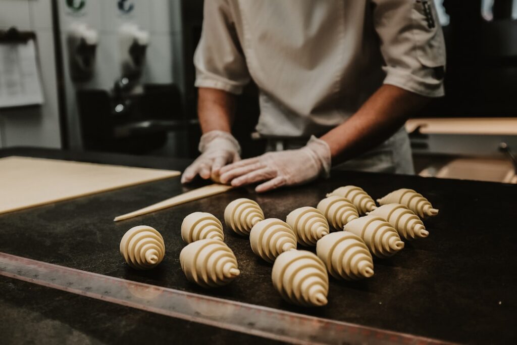 Hands rolling out croissant dough with a butter block illustrating the lamination process