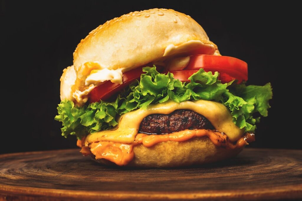 A close-up shot of a gourmet burger topped with a generous amount of homemade sauce fresh lettuce and tomato on a toaste