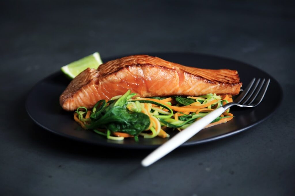 A grilled salmon fillet with lemon and herbs on a plate
